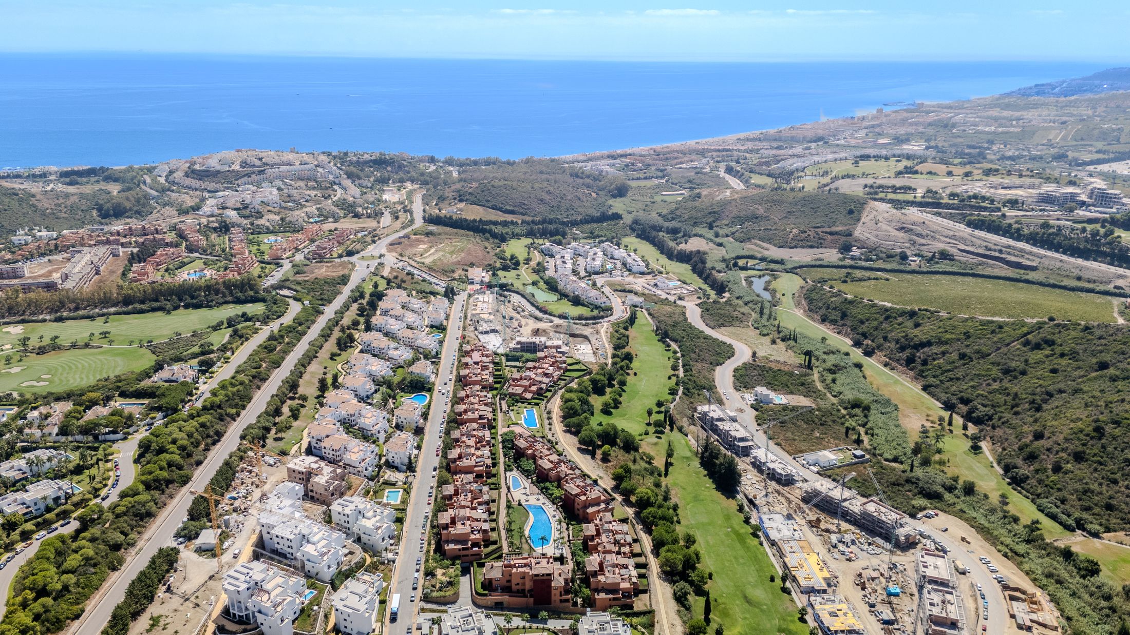 Aerial view over Casares Costa, golf fairways and terracotta homes towards the Mediterranean