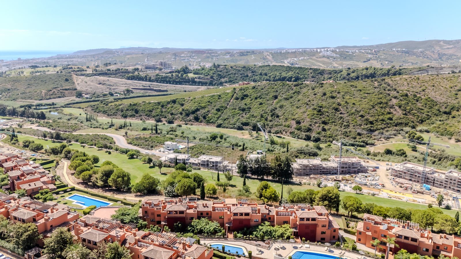 Green valley, golf course and hills behind terracotta homes