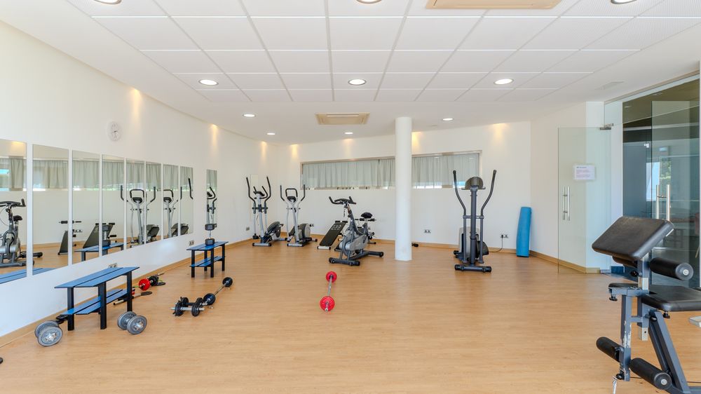 Bright on-site gym with exercise equipment and large windows