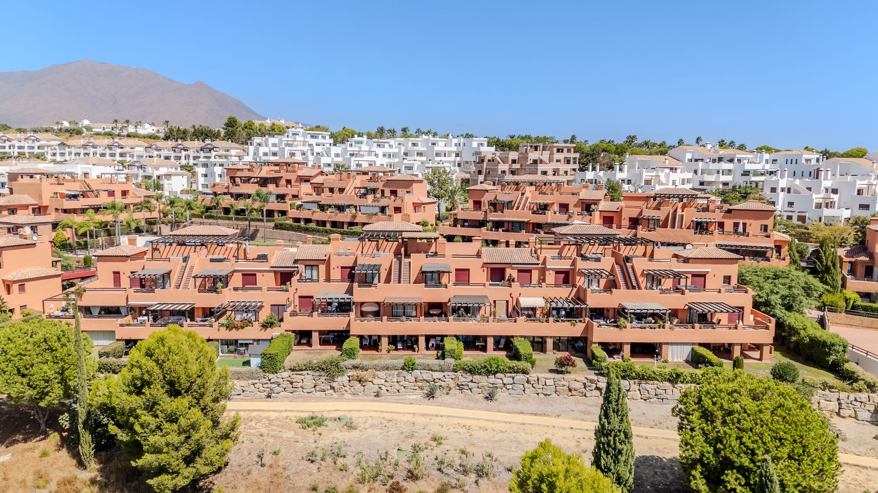 Terracotta apartment buildings with terraces, pines and cypress trees on the hillside
